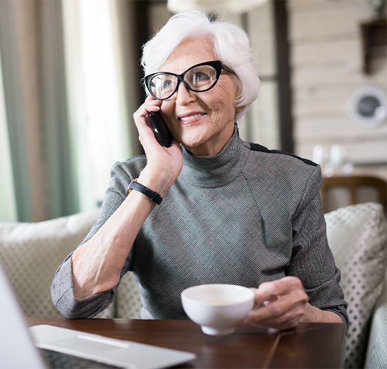 smiling senior woman on the phone while drinking coffee guaranteed retirement income white bear lake mn